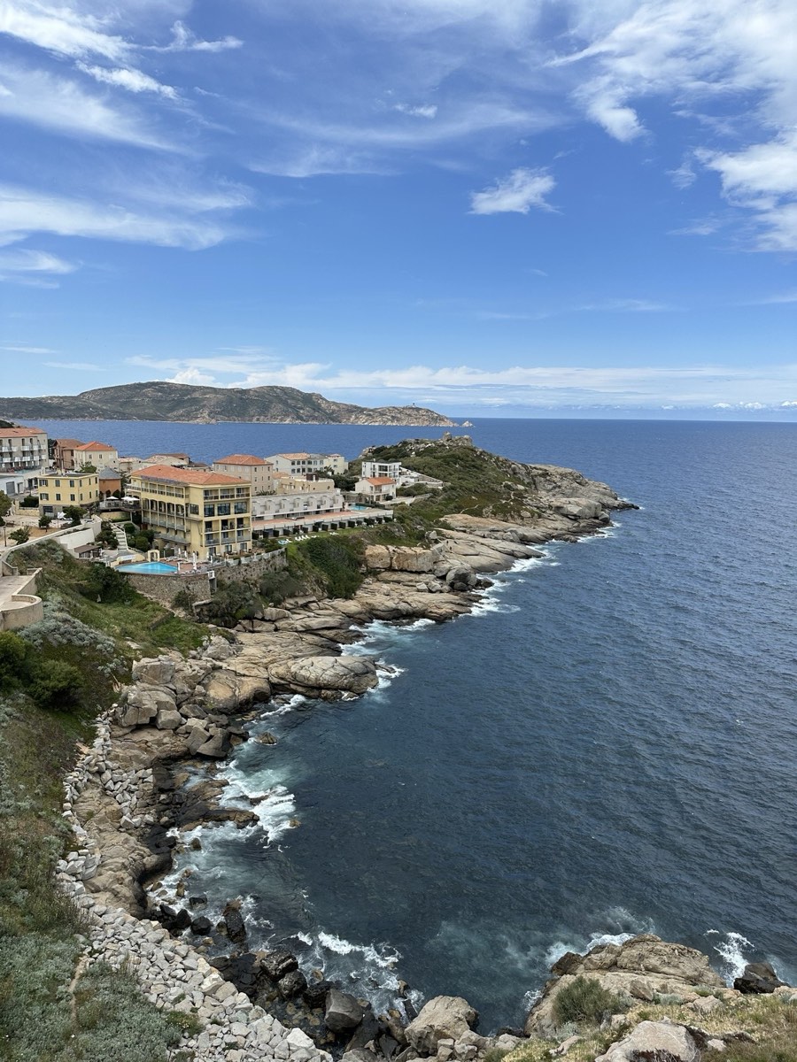 Corsica coastline viewed from an airplane window, the wing cutting across the turquoise sea